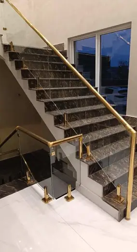 Gold fitting glass railing dark marble stairs