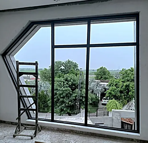 Large angled black frame aluminium window with garden view