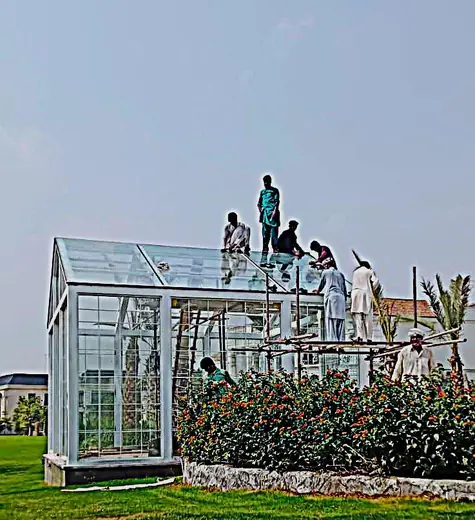 Glass roof house structure being installed in a garden